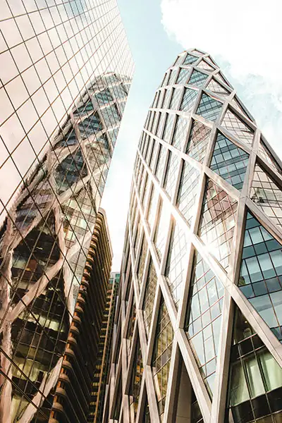 Low-angle view of a glass skyscraper reflecting the sky, symbolizing scalable code and enterprise-grade web development.